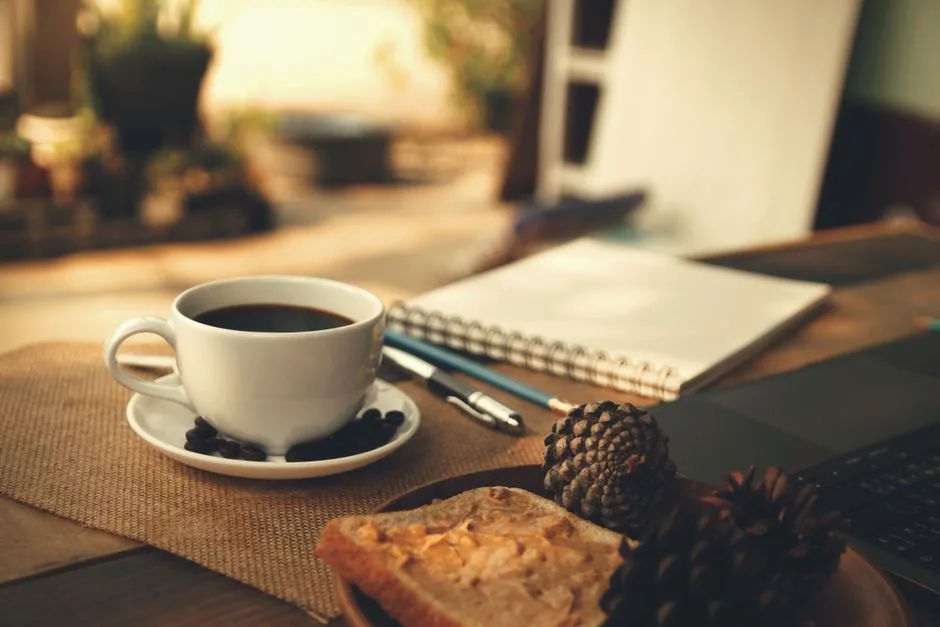 Table de travail en lumière du matin, carnet ouvert et tasse de café